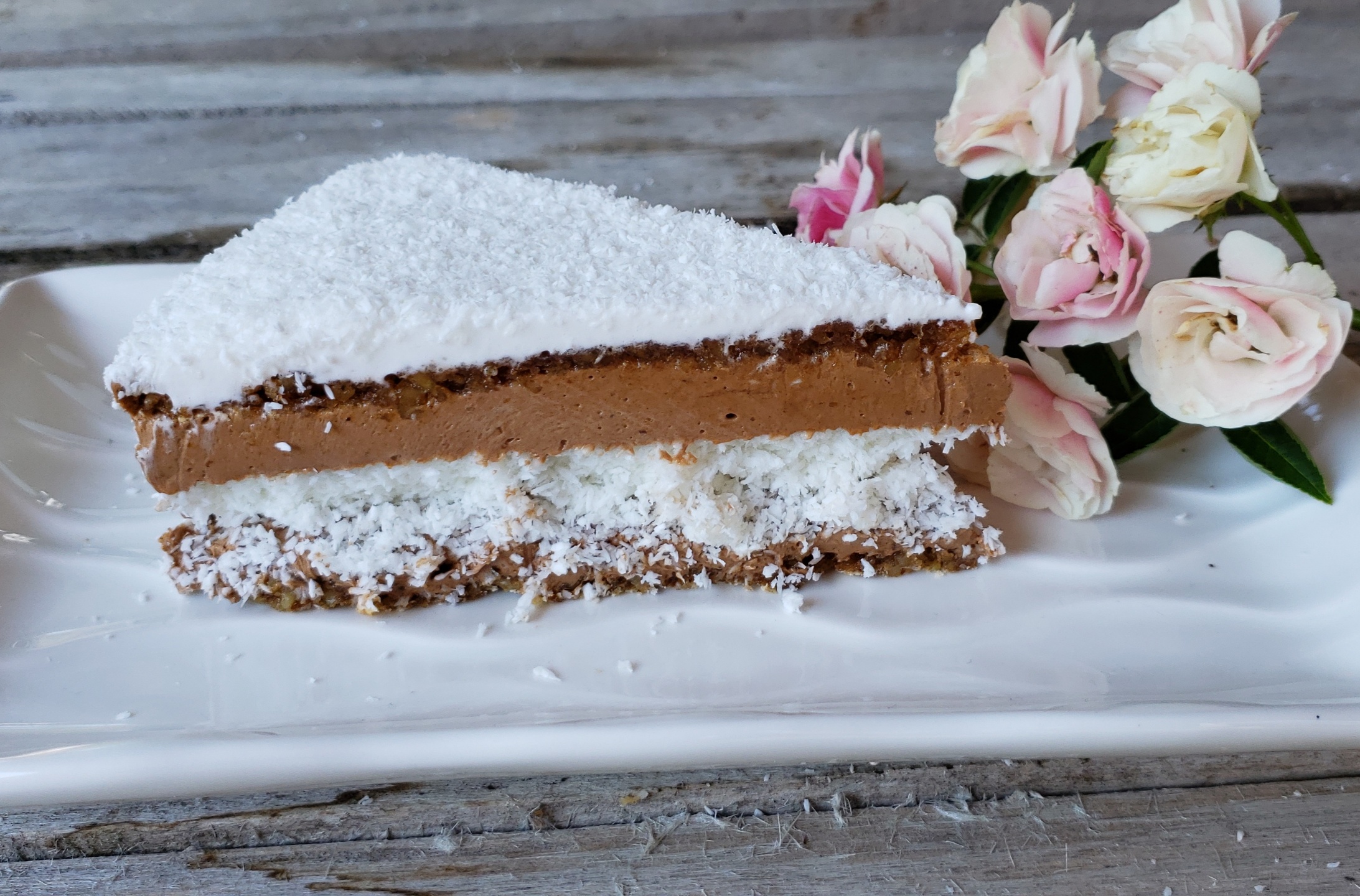 A piece of gluten free coconut cake, filled with chocolate filing, and coconut filing
